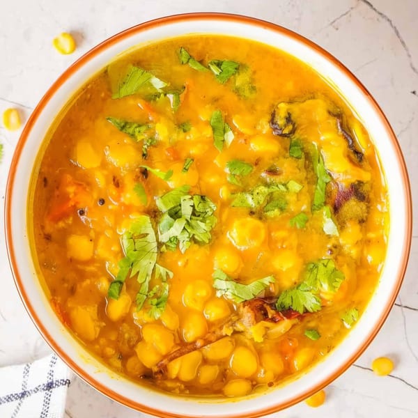 Close-up of a bowl of yellow Indian chana dal, garnished with fresh green cilantro.