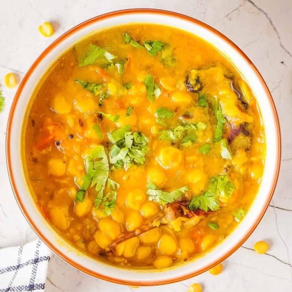 Overhead view of a bowl of yellow Indian dal with chickpeas and cilantro garnish.