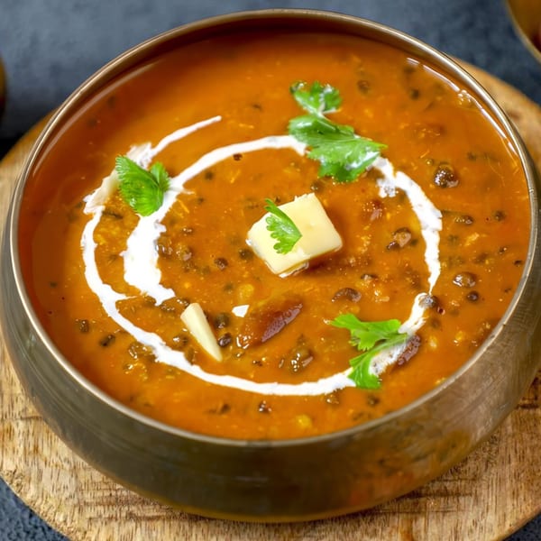A golden bowl of Desi Mama's Indian Dal Makhani, garnished with cream, butter, and cilantro.